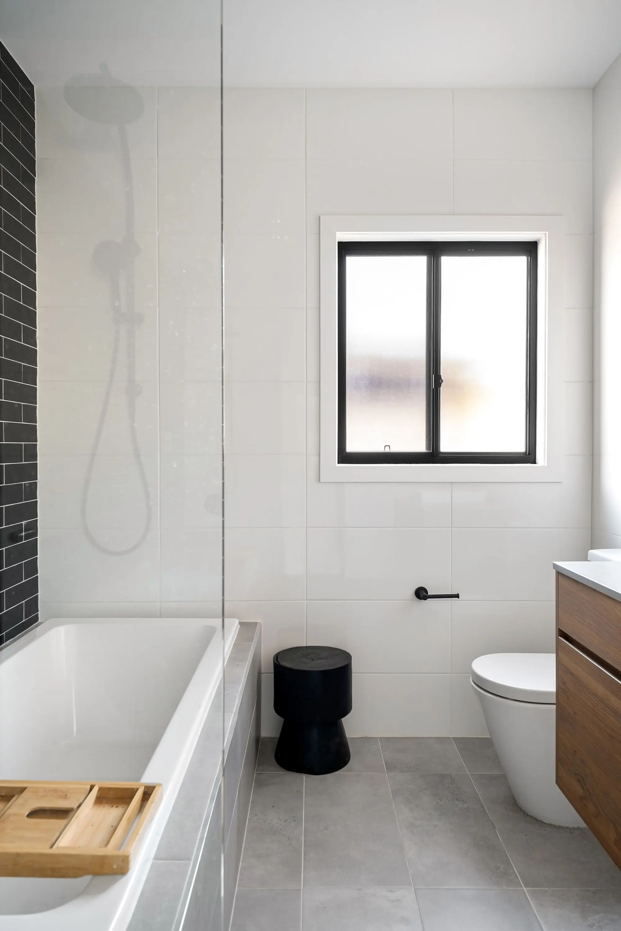 Remodeled bathroom with white marble tile, black fixtures and a freestanding tub