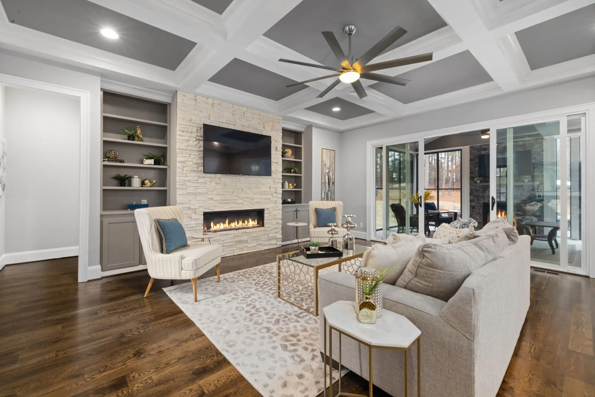 Living room with a painted coffered ceiling, stone fireplace and built-ins