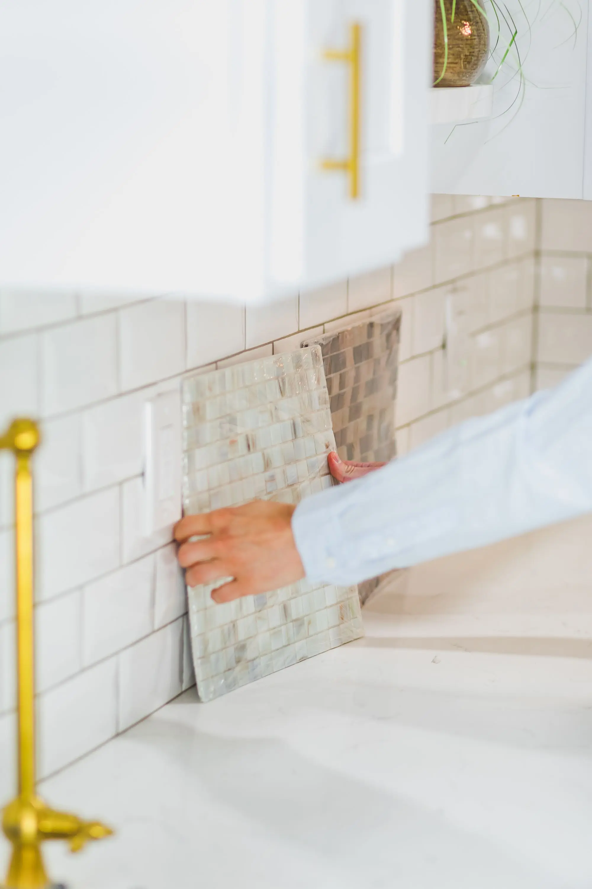 Hands setting a marble tile backsplash