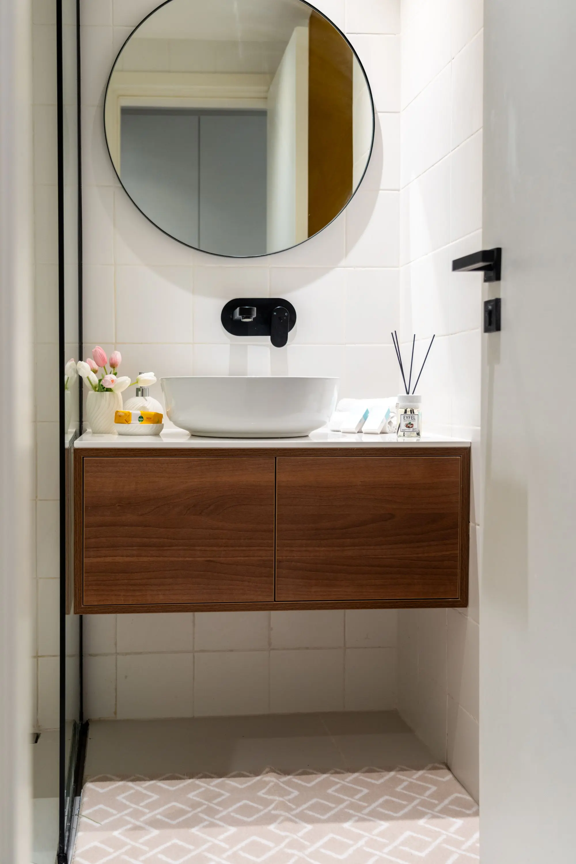 Powder room with a vessel sink, round mirror and tiled wall