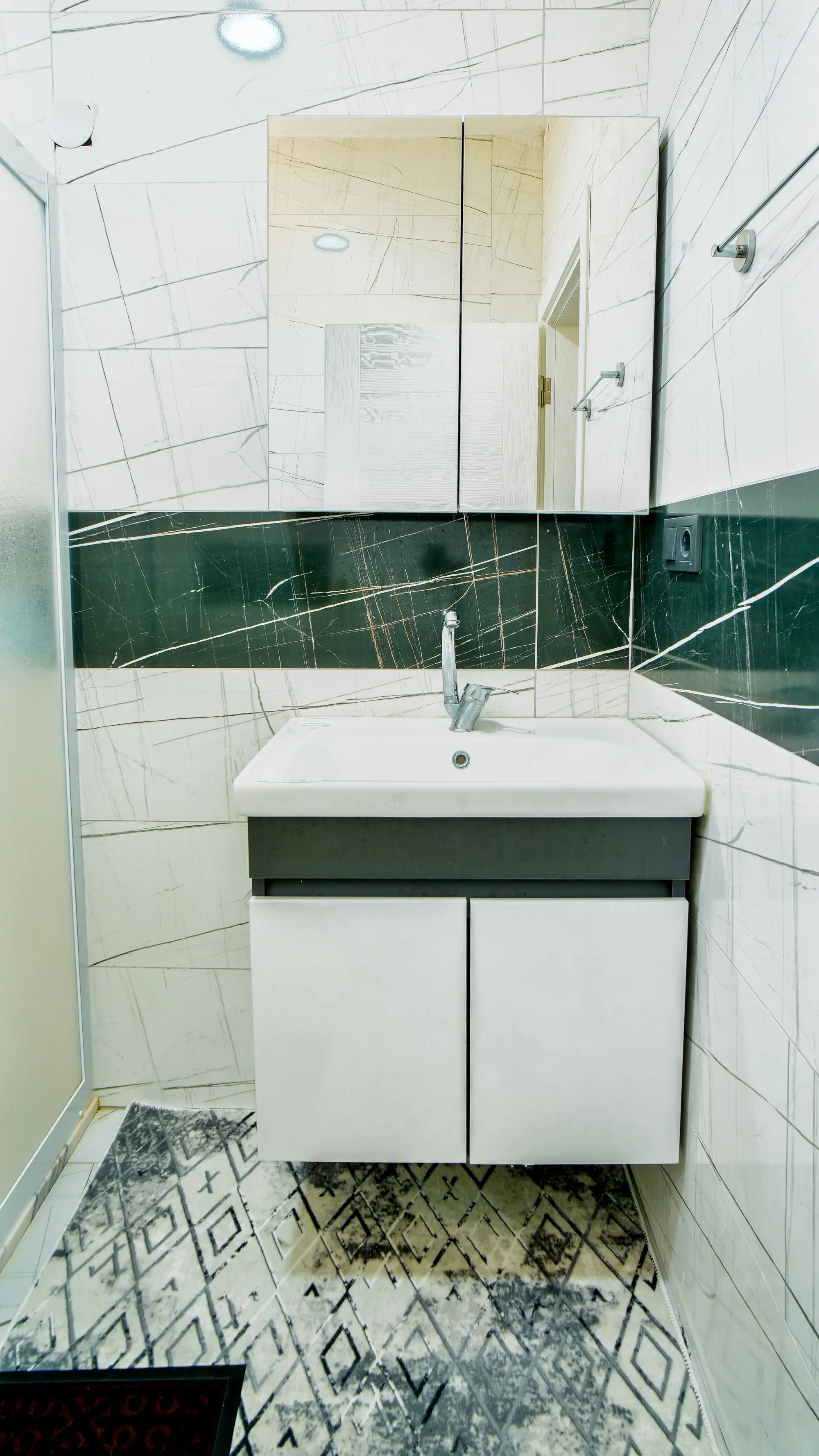 White bathroom with marble tile and a new vanity